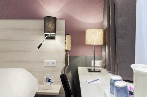 a hotel room with a bed and a phone on a desk at Kyriad Lille Est - Villeneuve d'Ascq in Villeneuve d'Ascq