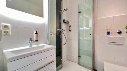 ein Bad mit einer Dusche und einem Waschbecken in der Unterkunft GreyPearl Appartement nahe Perlebucht mit Terrasse Parkplatz & WLAN in Büsum