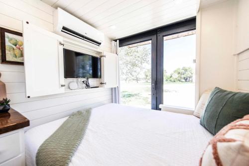 フレデリックスバーグにあるNew! Luxury Shipping Container The Desert Escapeのベッドとテレビ付きの小さな家のベッドルーム1室です。