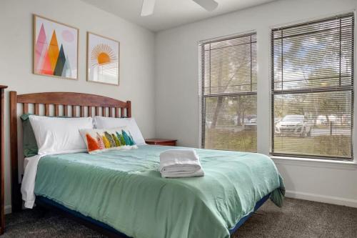 a bedroom with a bed with a green comforter and two windows at Family condo near Lettuce Lake in Tampa