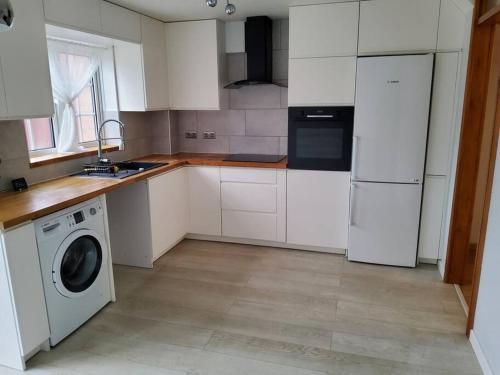 a kitchen with white cabinets and a washing machine at Primrose lodge cosy 2 bedroom house in a quiet in Norwich