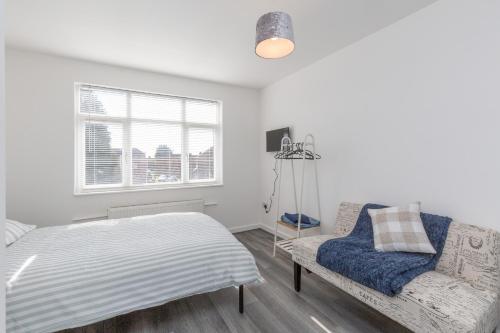 1 dormitorio con cama, sofá y ventana en 20 Leys Road rooms 1 - 4, en Wellingborough
