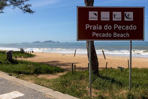 a sign in front of a beach with the ocean at Pousada Lazúli in Macaé