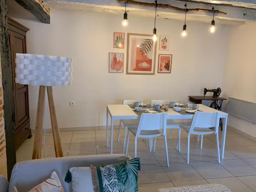 une salle à manger avec des tables blanches et des chaises blanches dans l'établissement Jolie maison avec cheminée, à la campagne, à Taïx