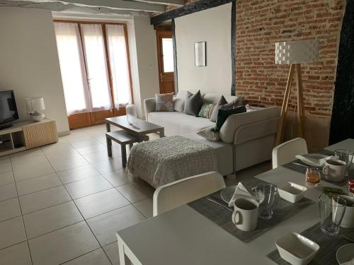 a living room with a couch and a brick wall at Jolie maison avec cheminée, à la campagne in Taïx