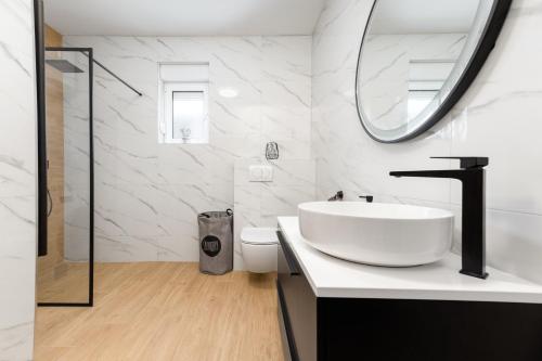 a white bathroom with a sink and a mirror at Holiday home Paligan in Solin