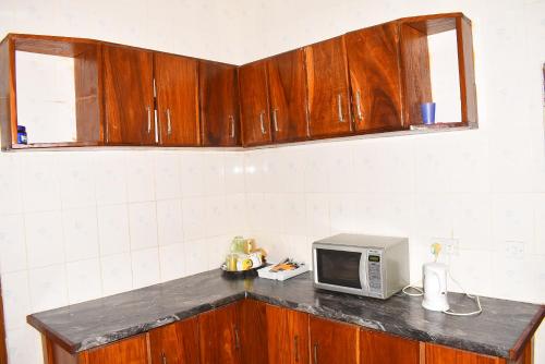 a kitchen counter with a microwave on top of it at Londoninnn in Bijilo