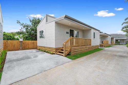 uma pequena casa branca com uma cerca de madeira em Tasman Holiday Parks - Beachaven em Waihi Beach