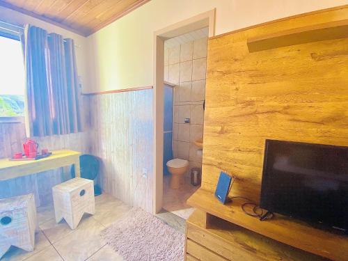 a living room with a television and a bathroom at Hospedaria Vila Rica - 1 km do centro histórico in Ouro Preto
