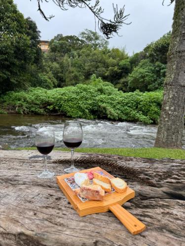 two glasses of wine and a tray of bread and cheese at Pousada Chalés Jardim das Bromélias - Visconde de Mauá in Visconde De Maua