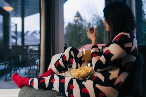 a woman sitting on a couch with a bowl of food at Beautiful Condo 3-Eleven at Tremblant in Mont-Tremblant