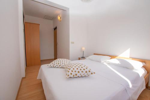a white bed with two pillows on top of it at Apartments Barbara in Pakoštane