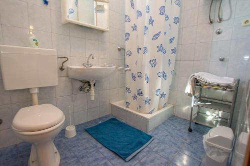 a bathroom with a toilet and a sink and a shower curtain at Apartments Barbara in Pakoštane