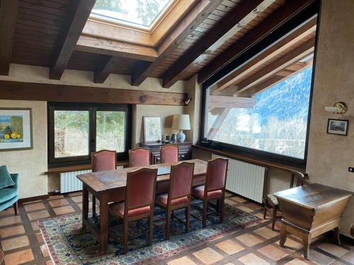 een eetkamer met een tafel, stoelen en ramen bij Relais Courmayeur - Fiore di bosco - Mont Blanc - Italia in Courmayeur