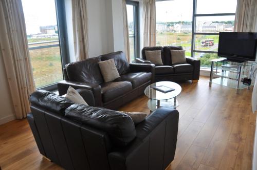 a living room with two leather couches and a television at Ocean Serviced Apartments in Edinburgh