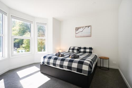 um quarto branco com uma cama e janelas em Modern Home Near Town em Dunedin