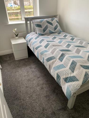 a bed with a blue and white comforter in a bedroom at Modern comfortable four bedroom house in great location in Dublin