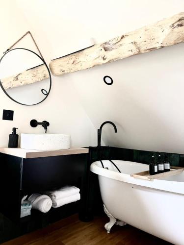 une salle de bain avec une baignoire, un lavabo et un miroir dans l'établissement Maison UMI, à Le Gigontier