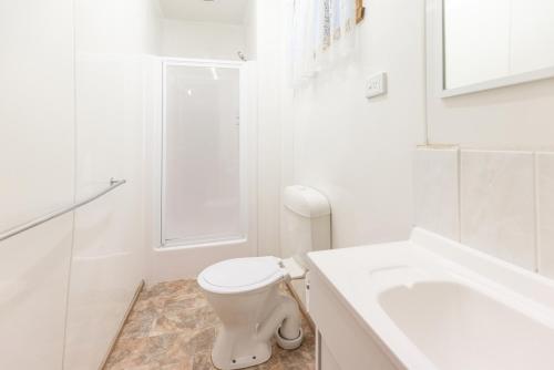 a white bathroom with a toilet and a sink at NRMA Warrnambool Riverside Holiday Park in Warrnambool