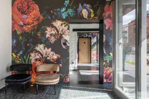 a hallway with two chairs and a wall with flowers at URBAN HOTEL in Debrecen