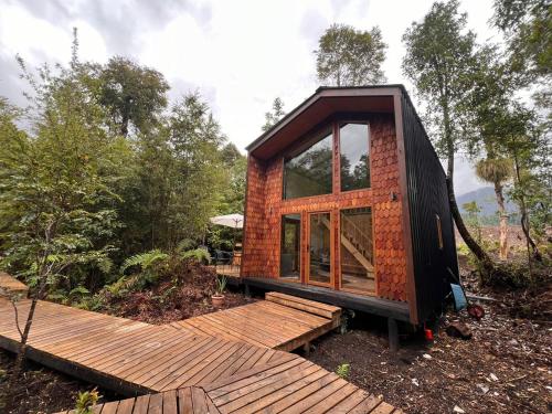 une petite maison assise au-dessus d'une terrasse en bois dans l'établissement Panigal, à Hornopirén