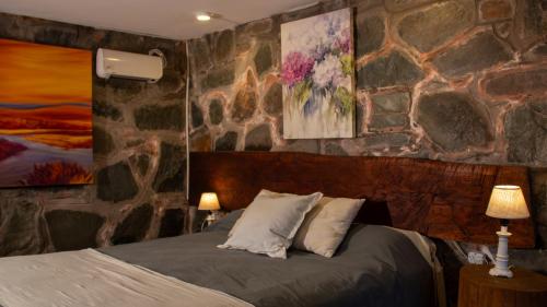 a bedroom with a stone wall with a bed at La Pedra Hotel Boutique, Raco in Raco