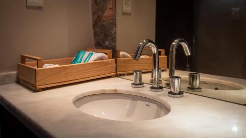 a bathroom sink with two faucets and a mirror at La Pedra Hotel Boutique, Raco in Raco