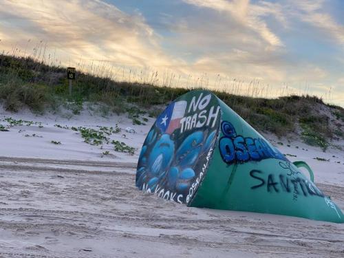 a surfboard laying on the sand on a beach at Coronado Get-AWAY at Fantasy Circle in South Padre Island