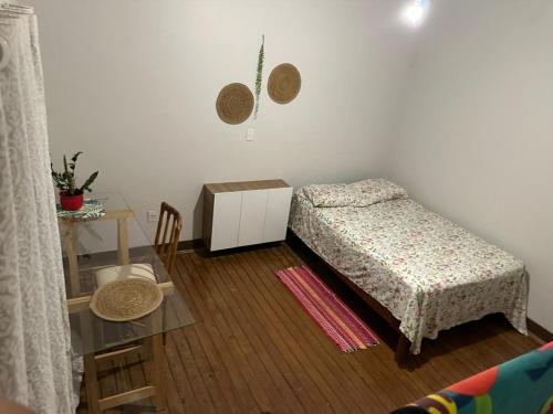 a small bedroom with a bed and a table at Hostel Namastê in Araraquara