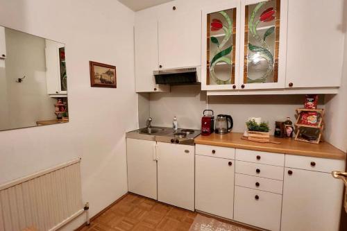 a kitchen with white cabinets and a sink at Innere Stadt Apartment (am Ring) in Vienna