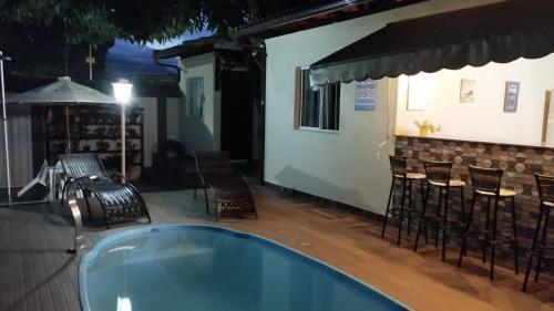 a swimming pool with chairs and a table and a bar at Casa c/ Piscina e Área Gourmet, 5 min da praia. in Guarapari