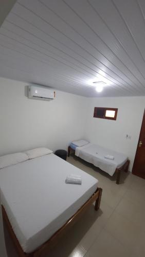 a room with two beds and a tv on the wall at Aloha Suites in Barra de São Miguel