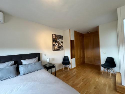 um quarto com uma cama e duas cadeiras pretas em Chalet IFema 5 Habitaciones 4 baños, parking free em Madri