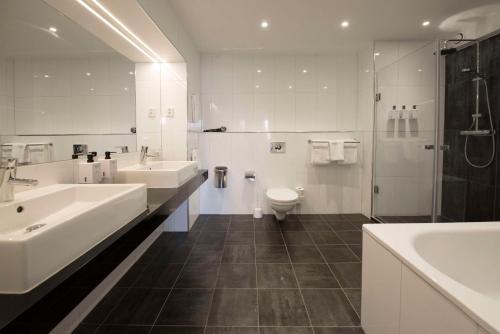 a bathroom with two sinks and a toilet and a shower at Scandic S:t Jörgen in Malmö