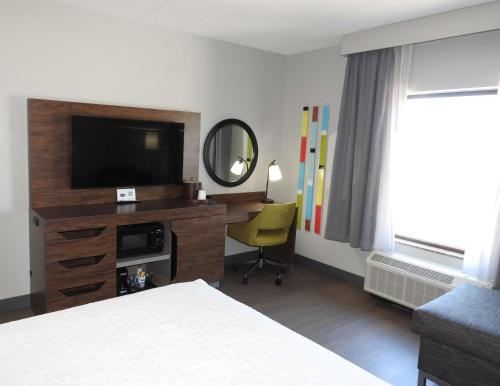 a hotel room with a television and a desk with a chair at Hampton Inn & Suites Flowery Branch in Flowery Branch