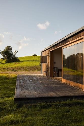 a house with a wooden deck in a field at Casa Avalon in Myocum