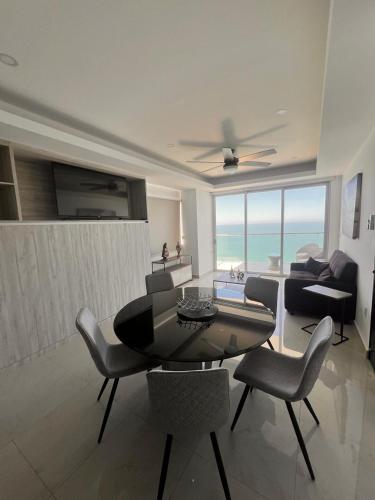 a living room with a table and chairs and the ocean at SUNSET VIEW MALECON MAZATLAN 1704 in Mazatlán