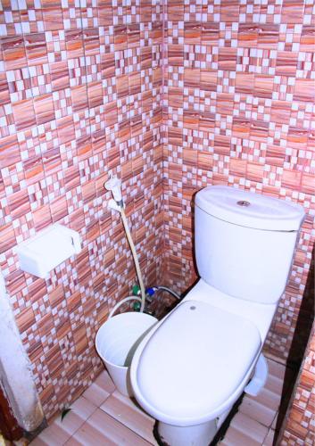 a bathroom with a toilet in front of a brick wall at KPR 2 in Addis Ababa