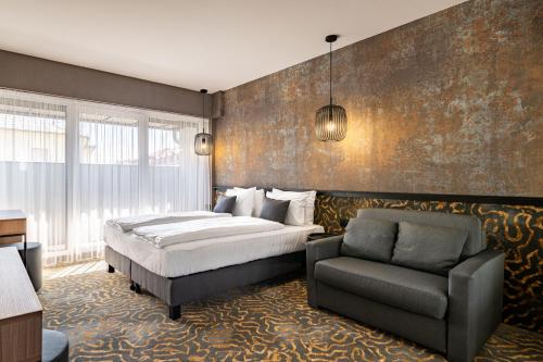 a bedroom with a bed and a chair at URBAN HOTEL in Debrecen