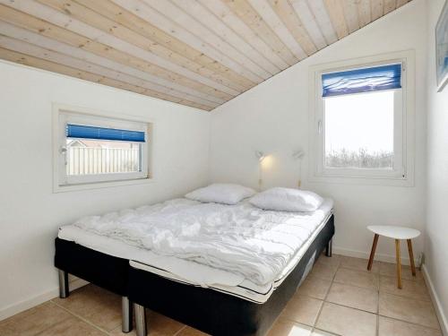 Dormitorio blanco con cama y mesa en Four-Bedroom Holiday home in Løkken 28, en Lønstrup