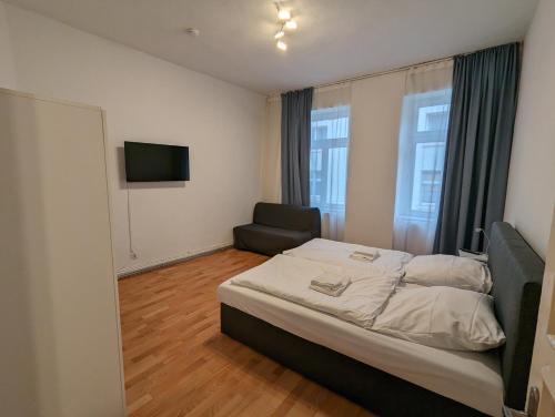 ein Schlafzimmer mit einem Bett und einem Stuhl und einem Fernseher in der Unterkunft Cityhouse - Wiesen in Wuppertal