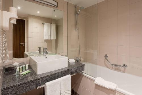 La salle de bains est pourvue d'un lavabo blanc et d'une douche. dans l'établissement Courtyard by Marriott Toulouse Airport, à Toulouse