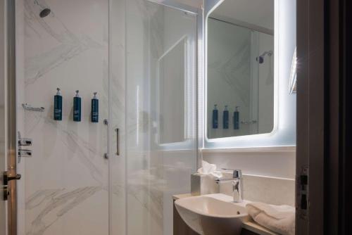 a bathroom with a sink and a shower with a mirror at DoubleTree by Hilton London Angel Kings Cross in London