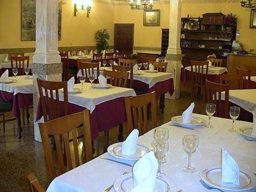 オカーニャにあるHotel Los Hermanosの白いテーブルクロスのテーブルと椅子が備わるレストラン