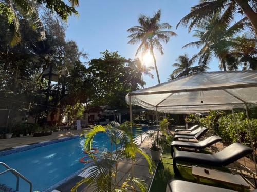 a swimming pool with lounge chairs and an umbrella at Ondas Do Mar Beach Resort Phase 1 in Calangute