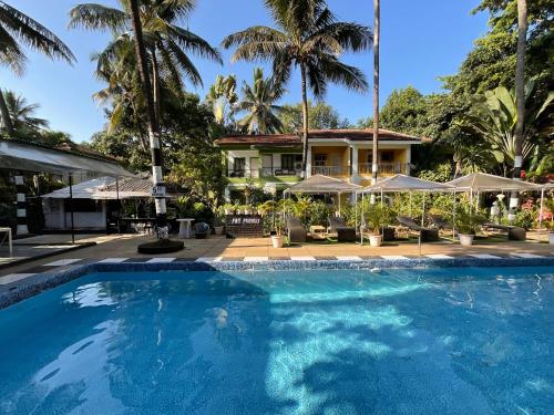 a swimming pool in front of a house with palm trees at Ondas Do Mar Beach Resort Phase 1 in Calangute