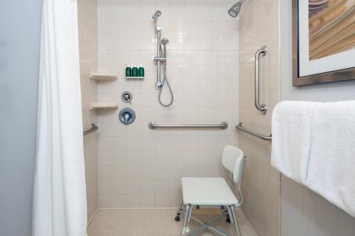 a shower with a white chair in a bathroom at Courtyard by Marriott Buffalo Airport in Cheektowaga