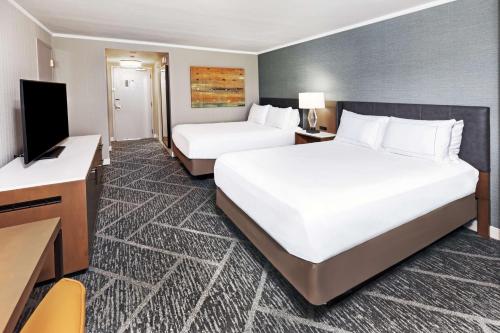 a hotel room with two beds and a flat screen tv at DoubleTree by Hilton Tulsa - Warren Place in Tulsa