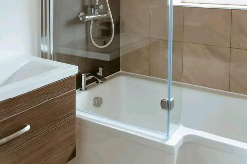 uma casa de banho com um chuveiro e uma banheira com uma porta de vidro em Home from Home in Tyne and Wear em Westoe
