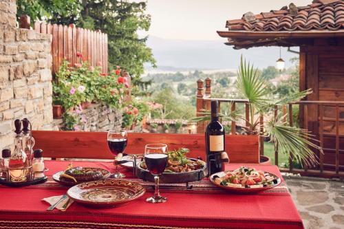 a table with plates of food and a bottle of wine at Yovina House Zheravna in Zheravna